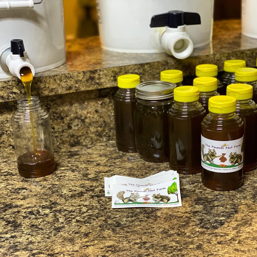 Honey pouring from a bucket gate into a bottle