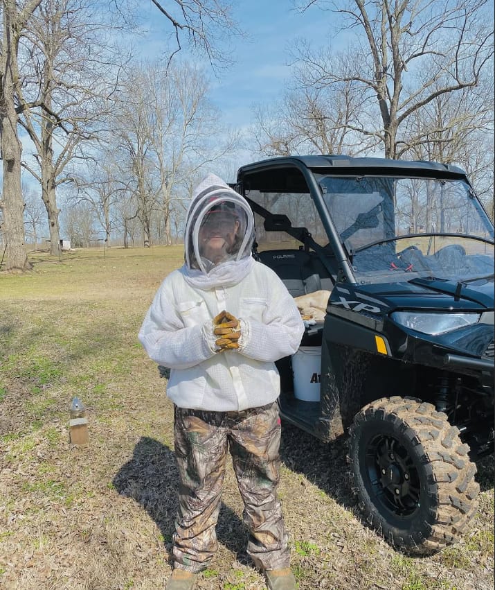 One of Toni's sons in a bee suit and gloves, helping out at the hives